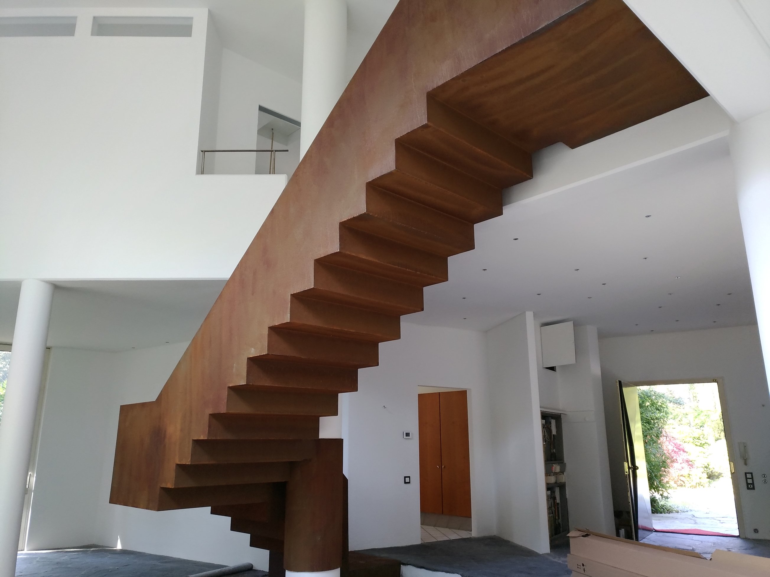 Innenarchitektur, frei stehende Treppe in Rostoptik als Blickfang im Raum.