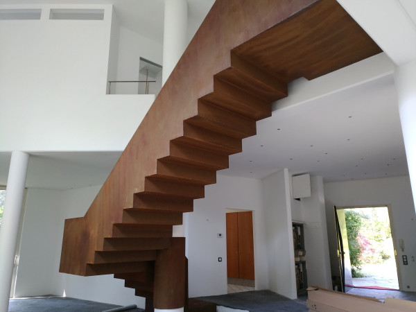 Innenarchitektur, frei stehende Treppe in Rostoptik als Blickfang im Raum.
